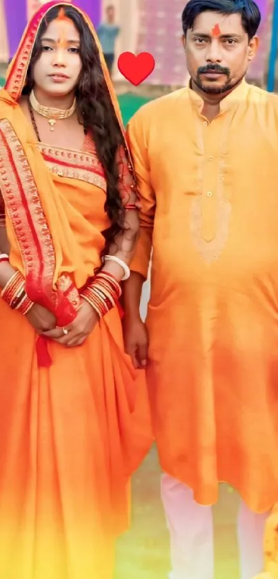 A couple in vibrant orange traditional Indian attire standing together.