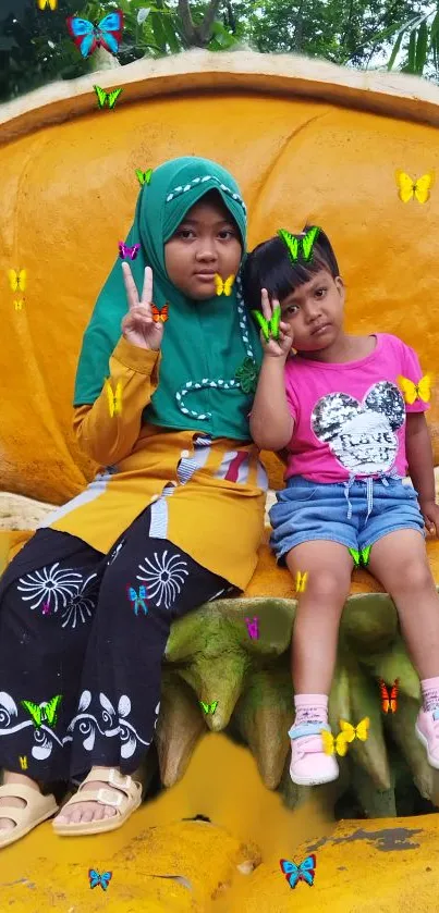 Two kids sitting surrounded by colorful butterflies on a bright yellow seat.