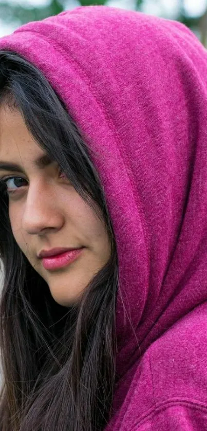 Person in a vibrant magenta hooded garment, stylish and artistic portrait.