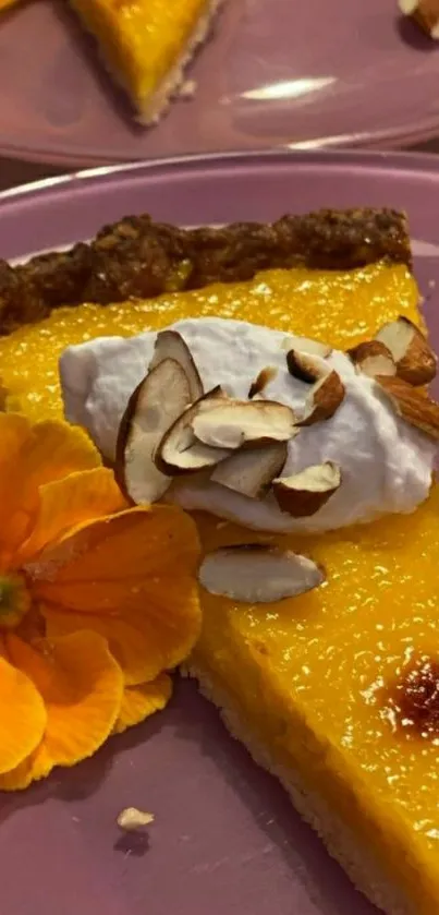 Vibrant mango tart with almond slivers and floral accent on a plate.