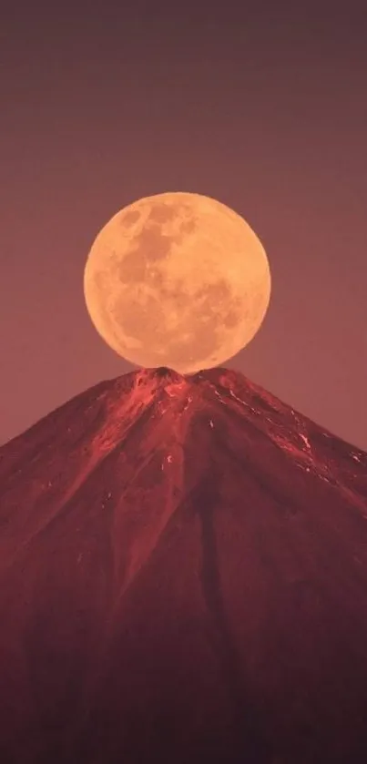 Majestic mountain with full moon overhead in a reddish-brown night sky.