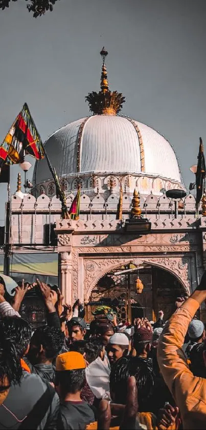 Festival crowd at a mosque with vibrant flags and architecture.