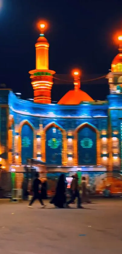 Night view of an illuminated mosque with vibrant orange minarets.