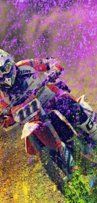 Motocross rider in a splash of vibrant pink, orange, and purple colors on a dirt track.