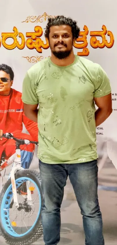 Figure in green shirt stands by colorful poster of motorcycle.