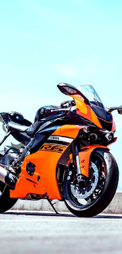 Orange and black motorcycle under a blue sky, perfect for dynamic mobile wallpaper.