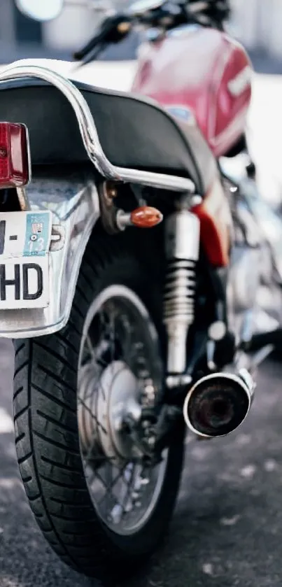 Rear view of vintage red motorcycle with chrome details on a road surface.