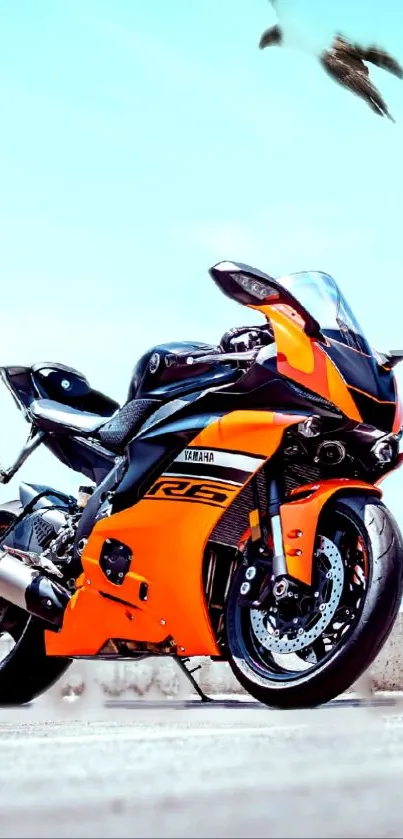 Vibrant orange motorcycle against blue sky on mobile wallpaper.