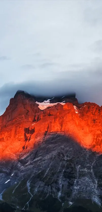 Vibrant sunset over rugged mountain peak with red-orange hues.