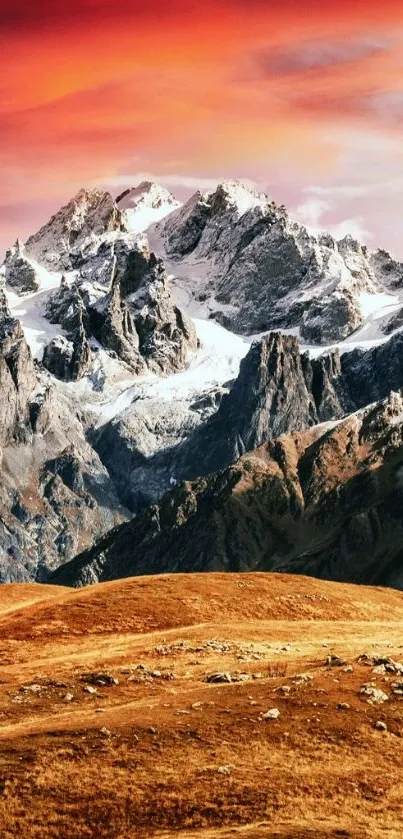 Vibrant sunset over snowy mountains and orange fields.