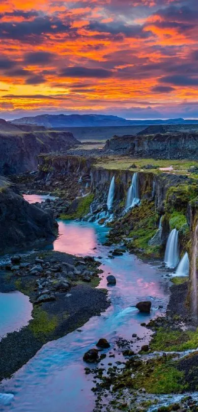 Vibrant mountain waterfall at sunset with colorful sky and serene landscape.