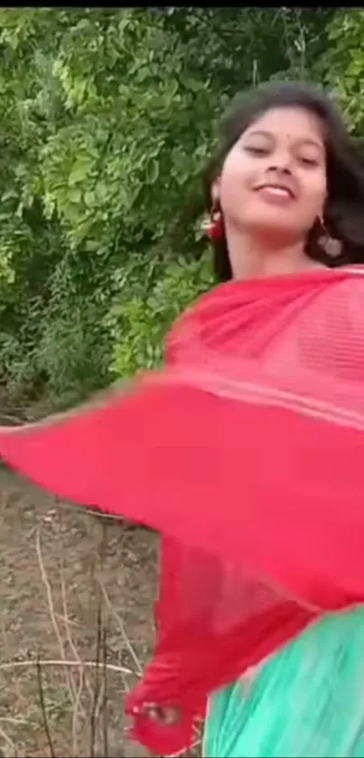 Woman joyfully dancing in nature with a red scarf.