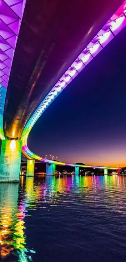 Vibrant neon bridge with colorful lights reflecting on water at night.