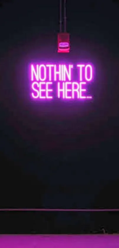 Neon pink 'Nothin' To See Here' sign on dark background.