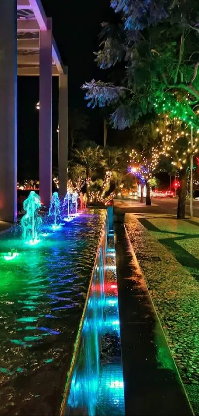 Illuminated night fountain with vibrant colors and trees.