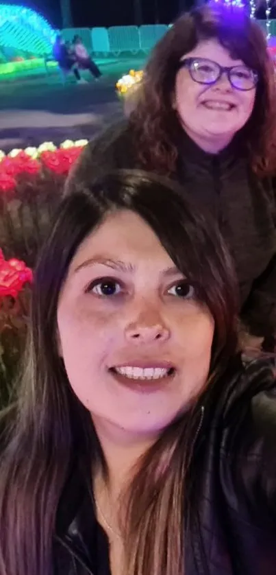 Vibrant night garden selfie with colorful lights and flowers.