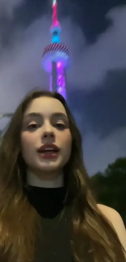 Young woman in front of a lit-up tower at night.