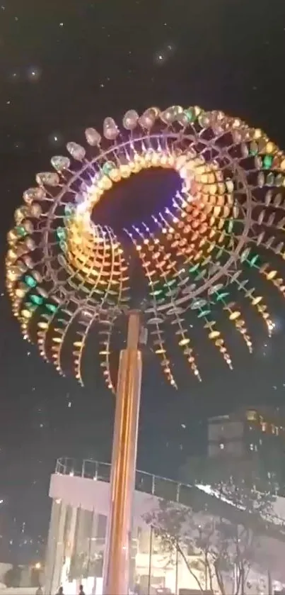 A vibrant spiral sculpture illuminated at night with colorful lights.