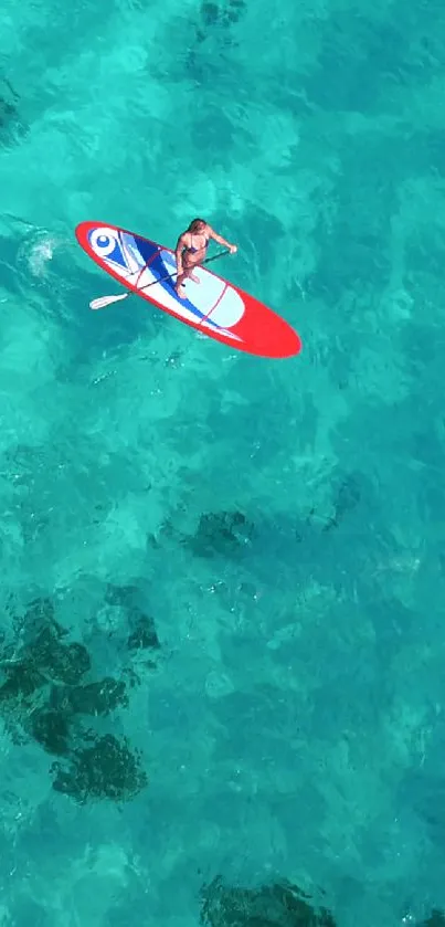 Aerial view of a lone paddleboarder on turquoise ocean waters.