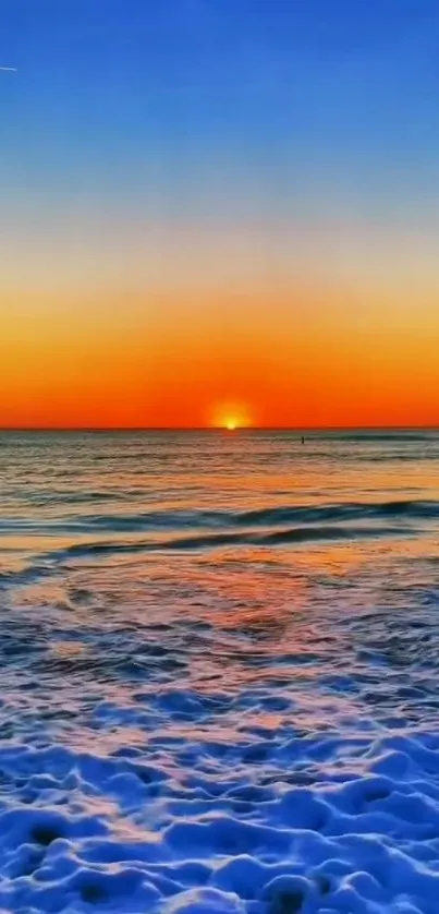 Vibrant ocean sunset with blue waves and orange sky.