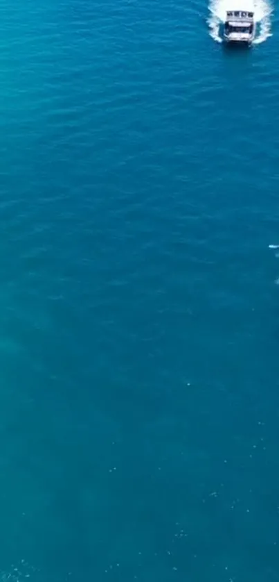 Turquoise ocean with boat creating white waves.