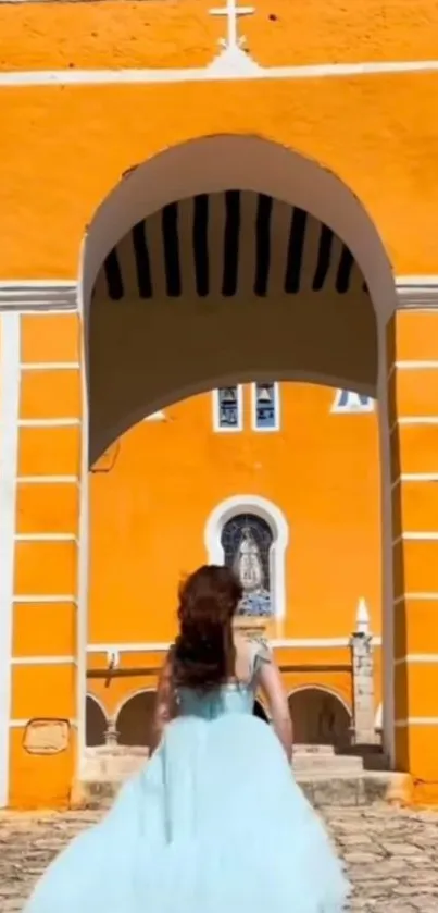 Woman in blue dress walking towards vibrant orange archway.