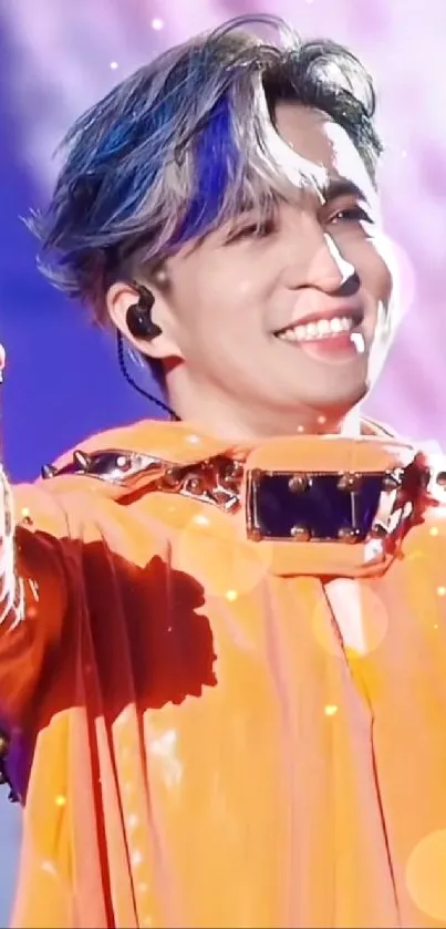 Energetic performer in orange outfit on vibrant concert stage.