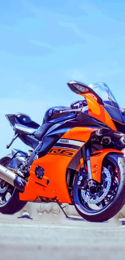 Vibrant orange motorcycle against a bright blue sky, perfect for mobile wallpaper.