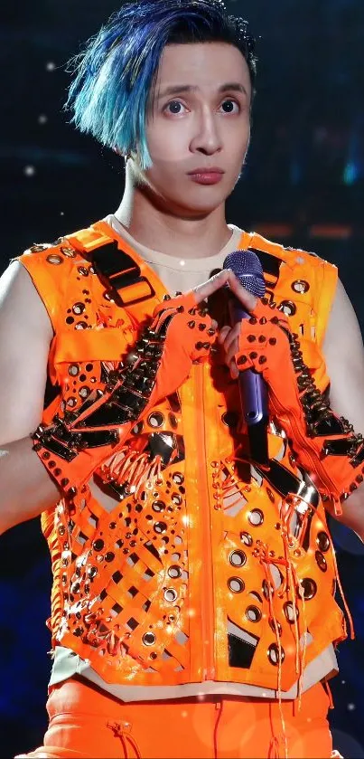 Performer in orange attire with blue highlights on stage.