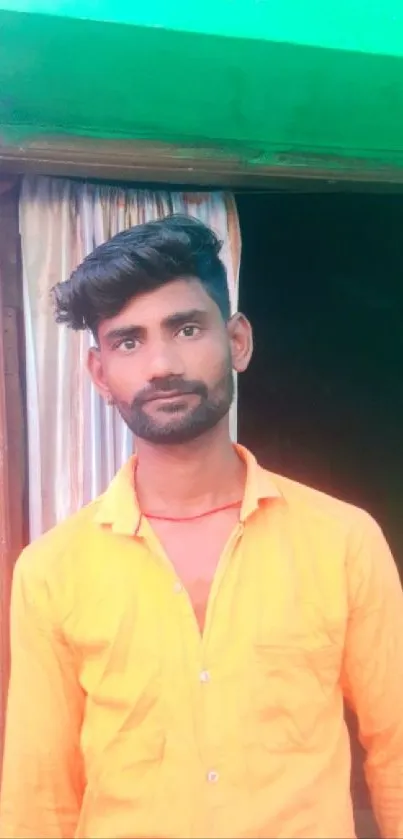 Man in vibrant orange shirt standing against a colorful background.