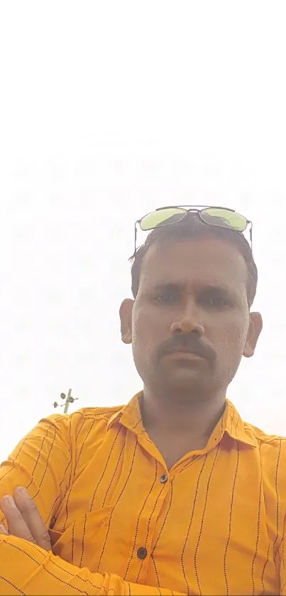 Man in a bright orange striped shirt with sunglasses, under a clear sky.