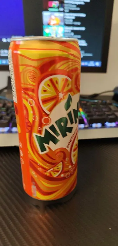 Vibrant orange soda can on desk with keyboard.