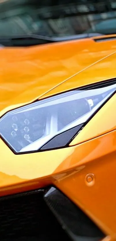 Close-up of vibrant orange sports car headlight.