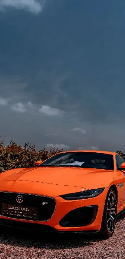 Vibrant orange sports car under cloudy sky.