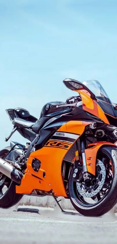 Orange sports motorcycle set against a bright blue sky.