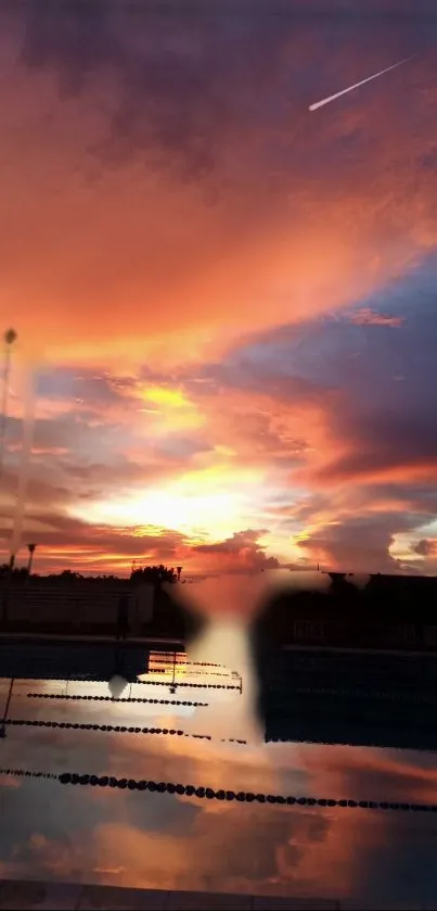 Orange sunset sky with clouds reflecting over a pool.