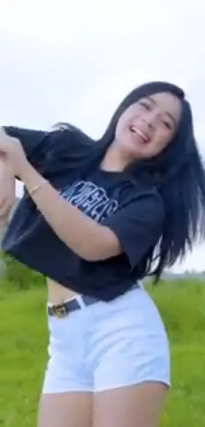 Woman joyfully dancing outdoors with a bright sky and green grass backdrop.