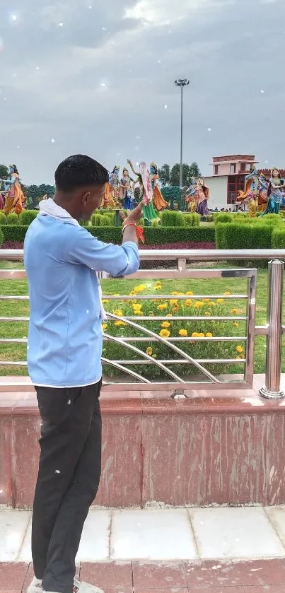 Person taking a photo in a colorful garden with sculptures.