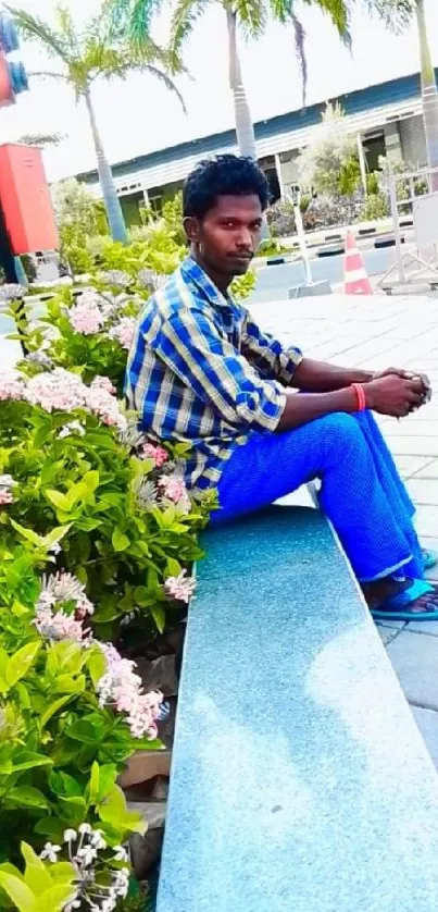 Man sitting on a garden bench with lush greenery and flowers.