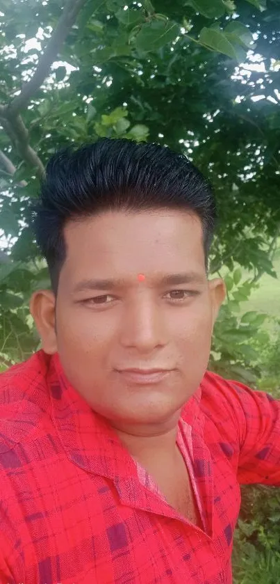 Outdoor portrait with greenery and a bright red shirt.