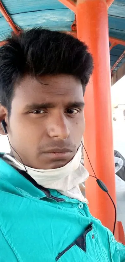 Portrait of a young man sitting at a bus stop with headphones.