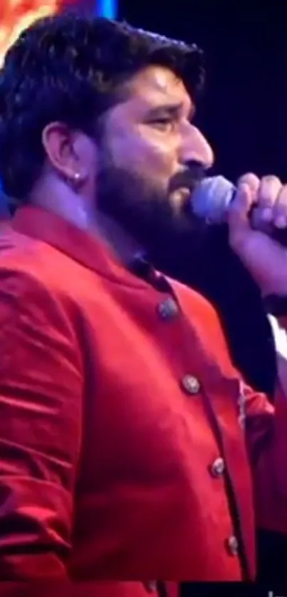 Performer singing passionately in a vibrant red jacket on stage.