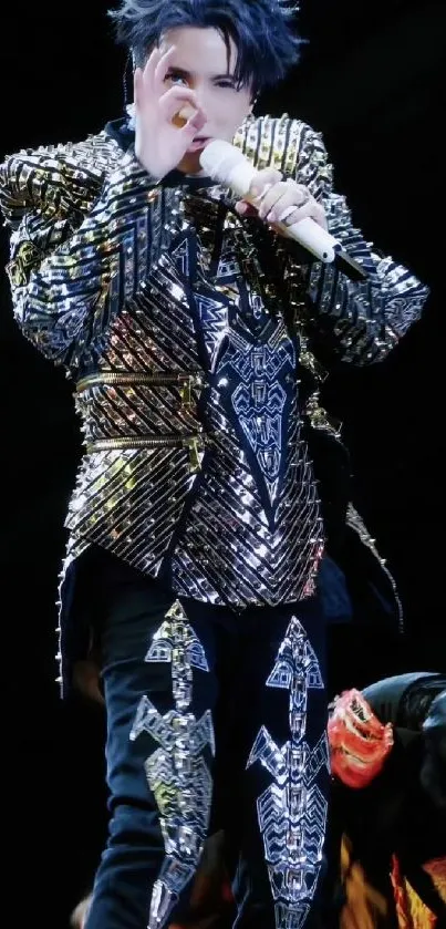 Performer in a metallic costume holding a microphone on stage.