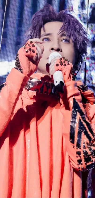 Performer in orange outfit with microphone on stage.