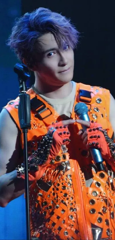 Performer with orange outfit and microphone on stage.