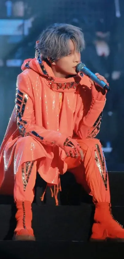 Performer in bright orange outfit on stage.