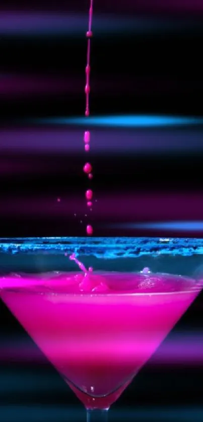 Pink cocktail splash in martini glass on black backdrop.