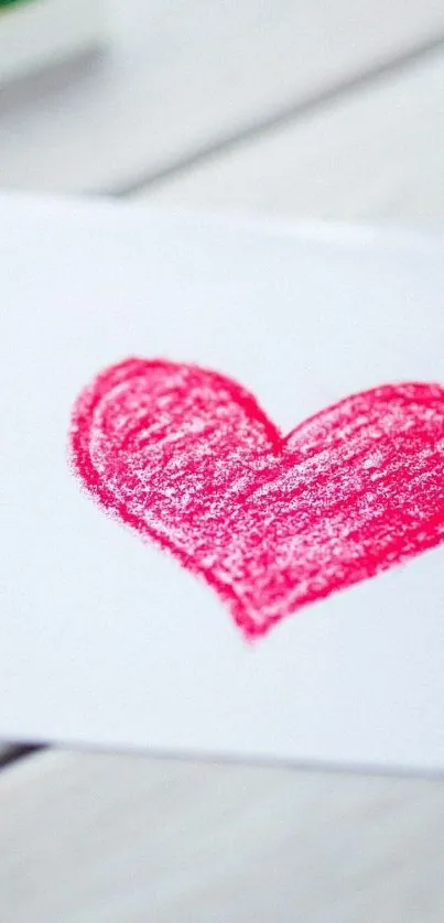 Vibrant pink crayon heart drawing on white.