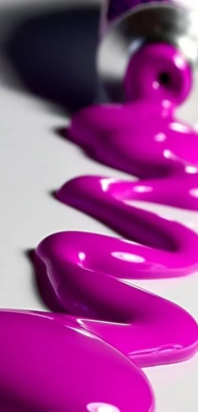 Close-up of vibrant magenta paint spilling from a tube on a white surface.