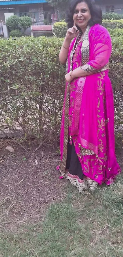 Woman in pink saree standing in garden, showcasing cultural fashion.